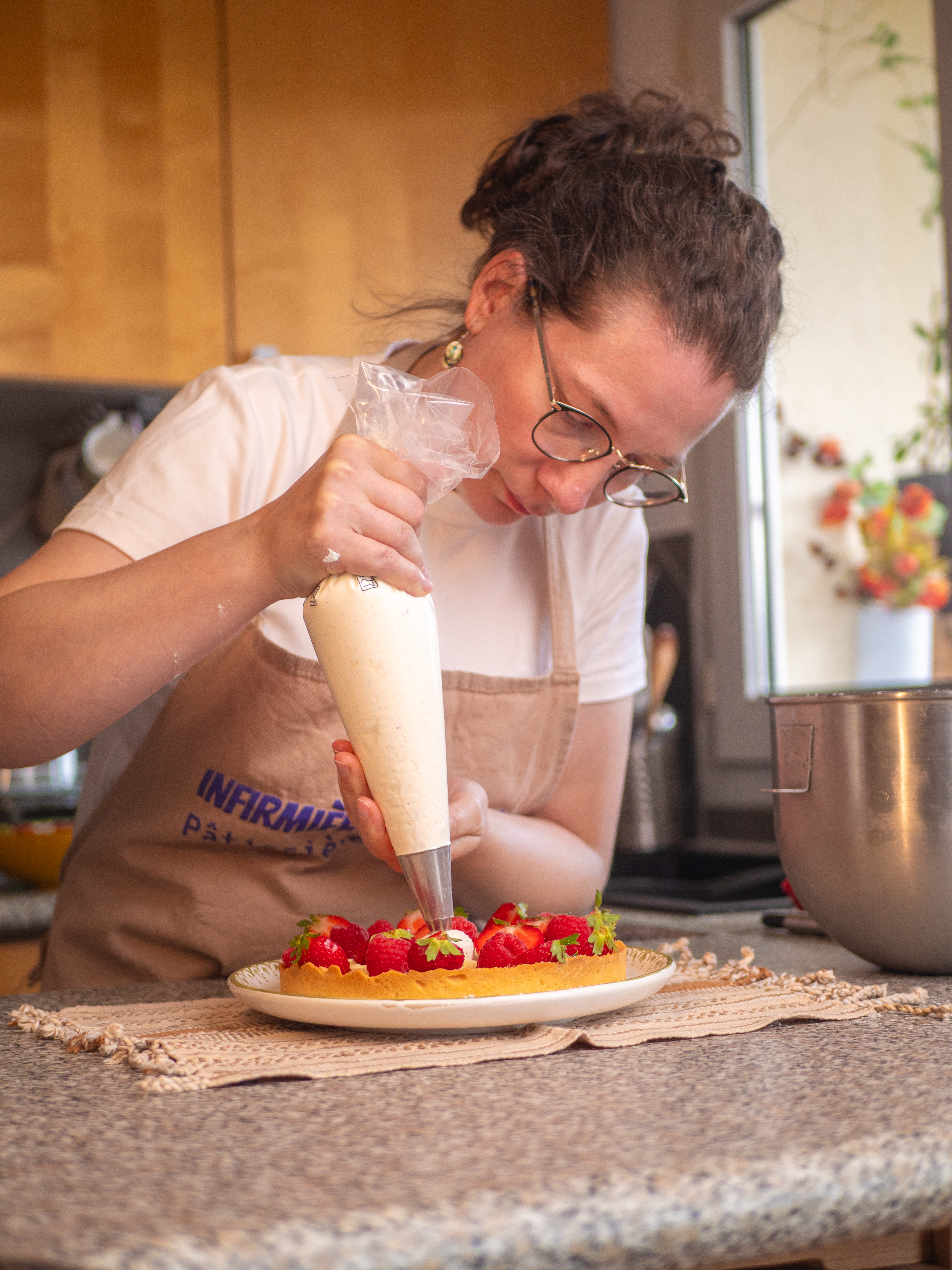 Aurore dresse la crème à la poche à douille sur une tarte aux fraises