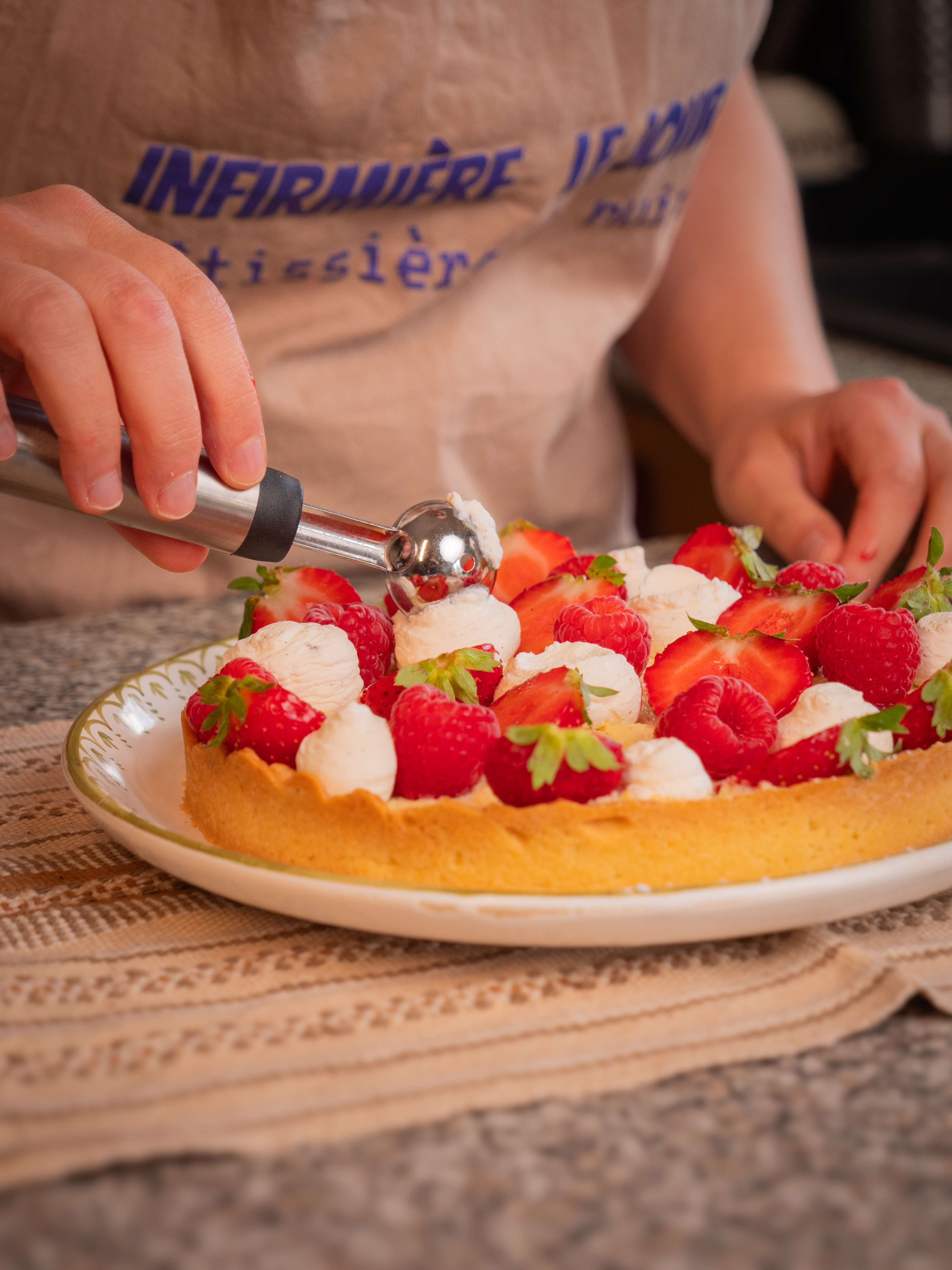 Aurore garnit une tarte aux fraises de boules de crème