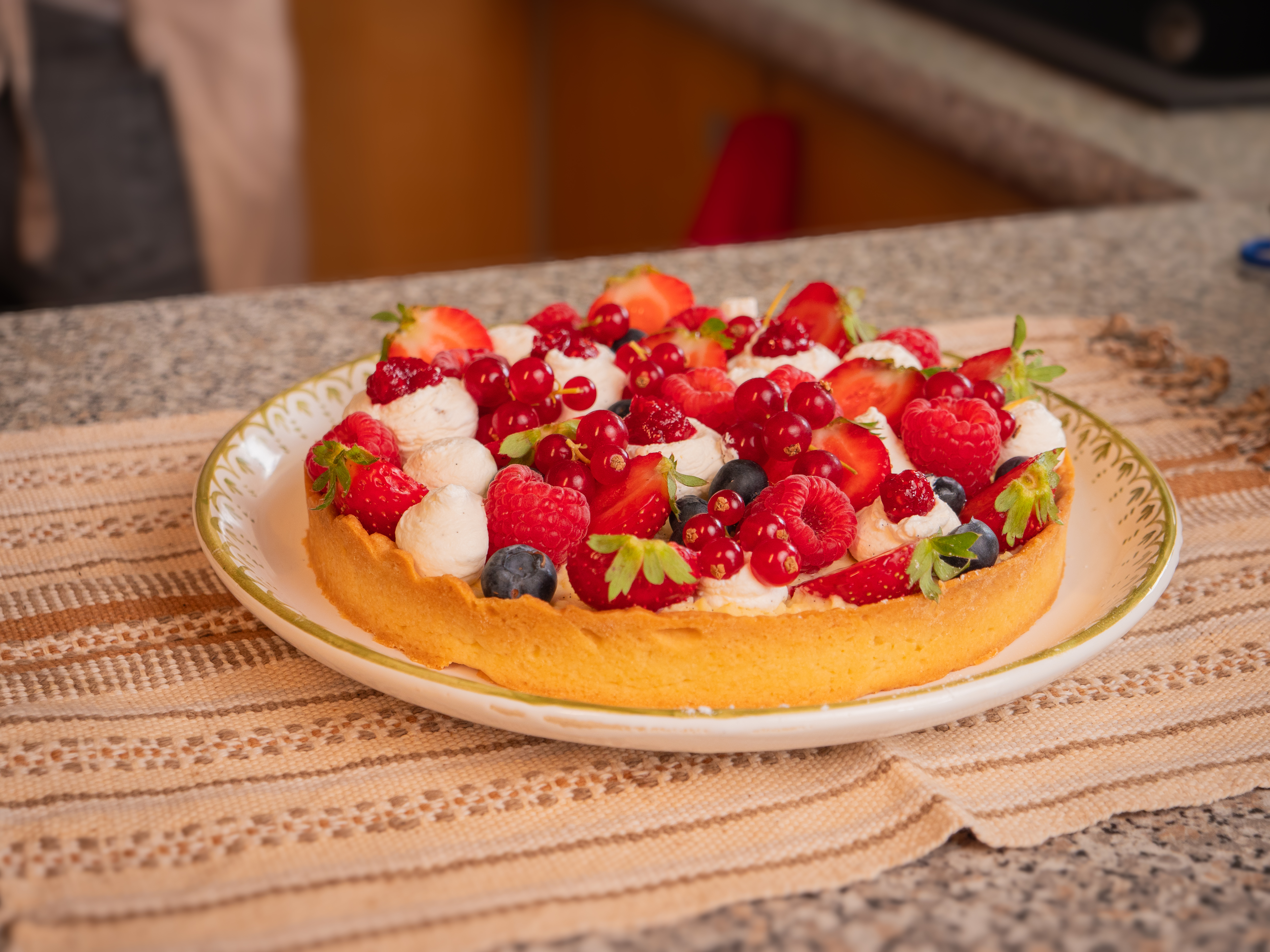 Tarte aux fruits rouges garnie de fraises, framboises, groseilles, myrtilles et crème