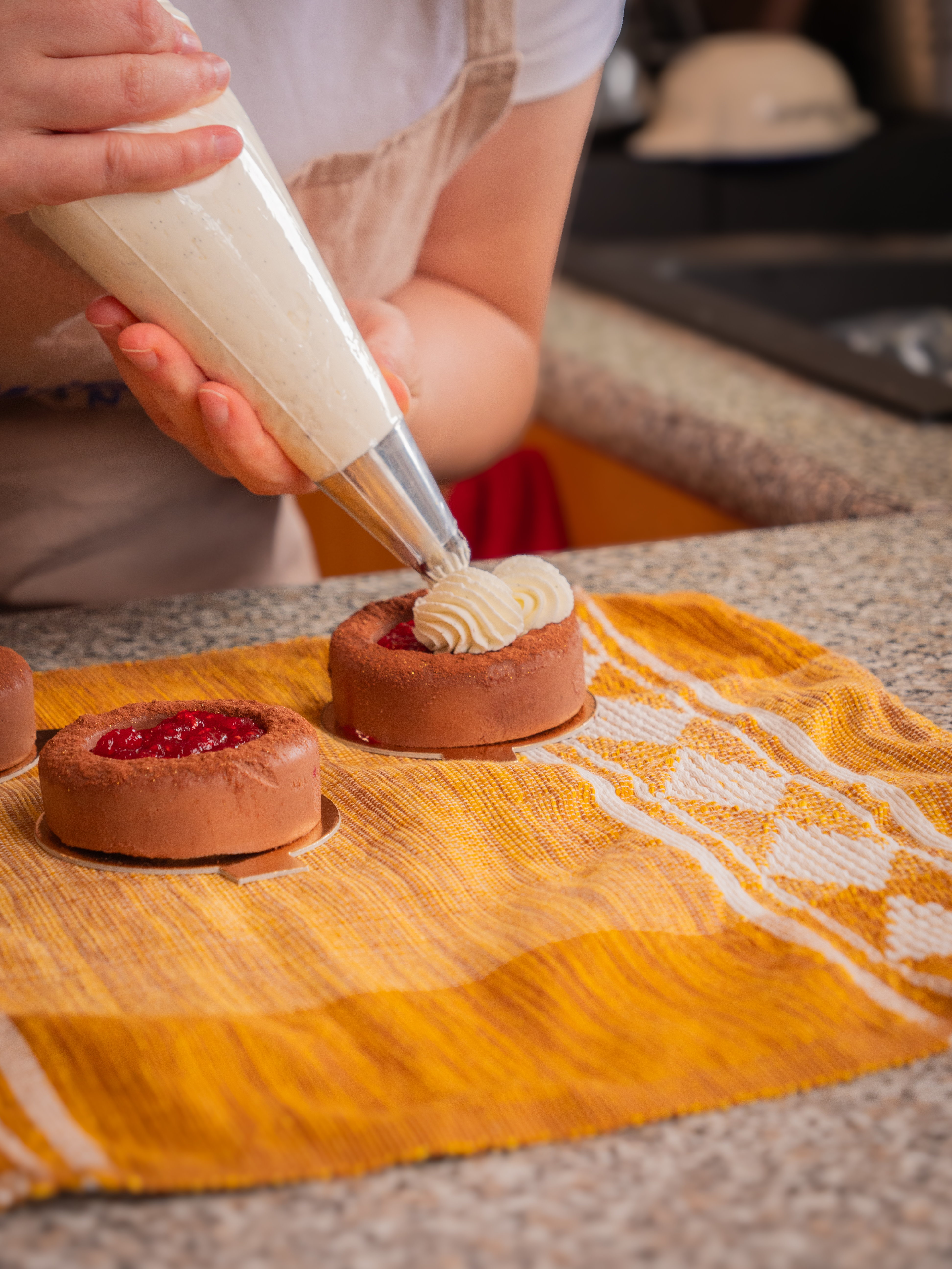Dressage de la crème à la poche sur une tartelette chocolat-framboise
