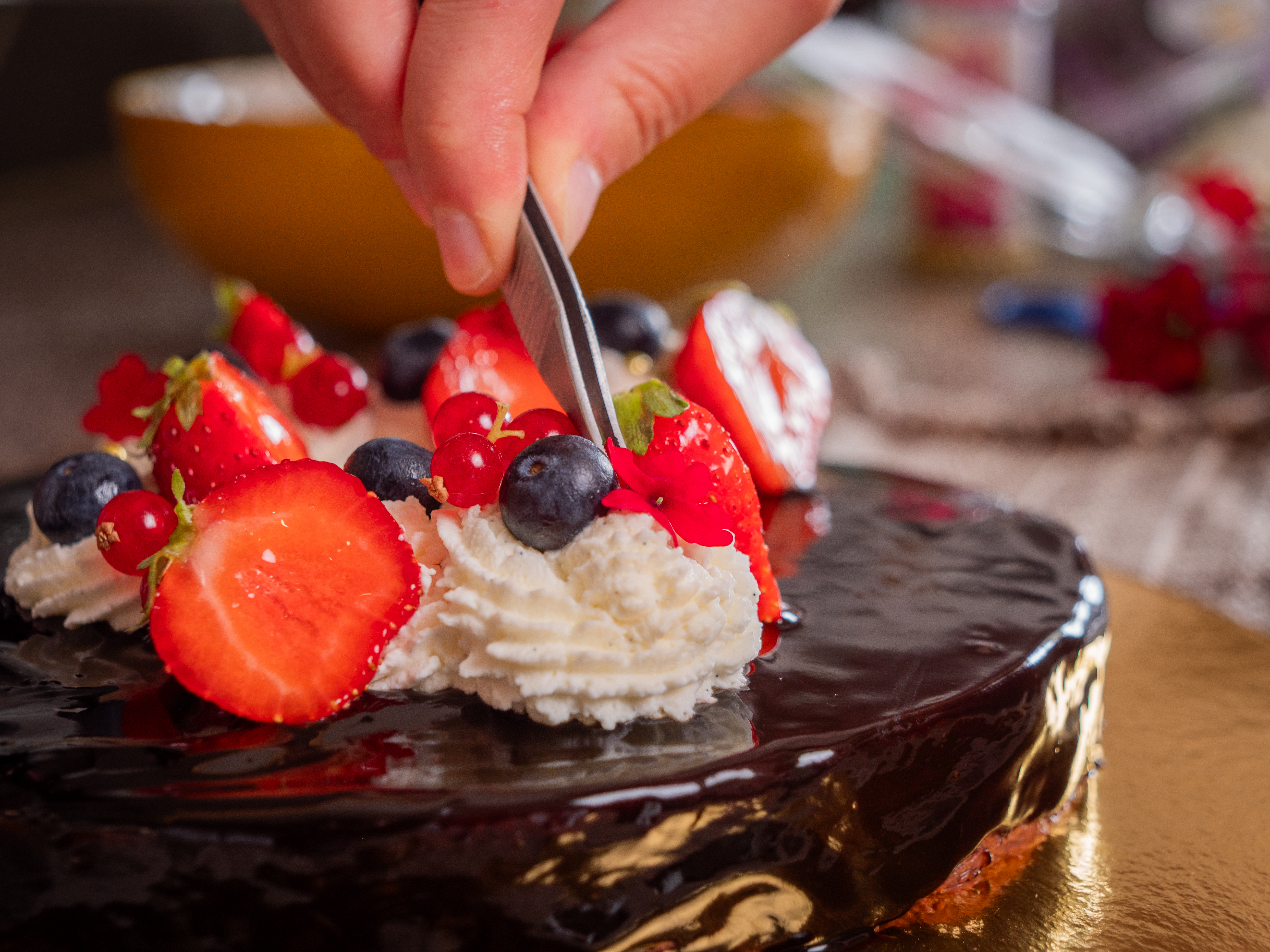 Entremets au glaçage miroir chocolat, décoré de rosaces de crème et de fruits rouges