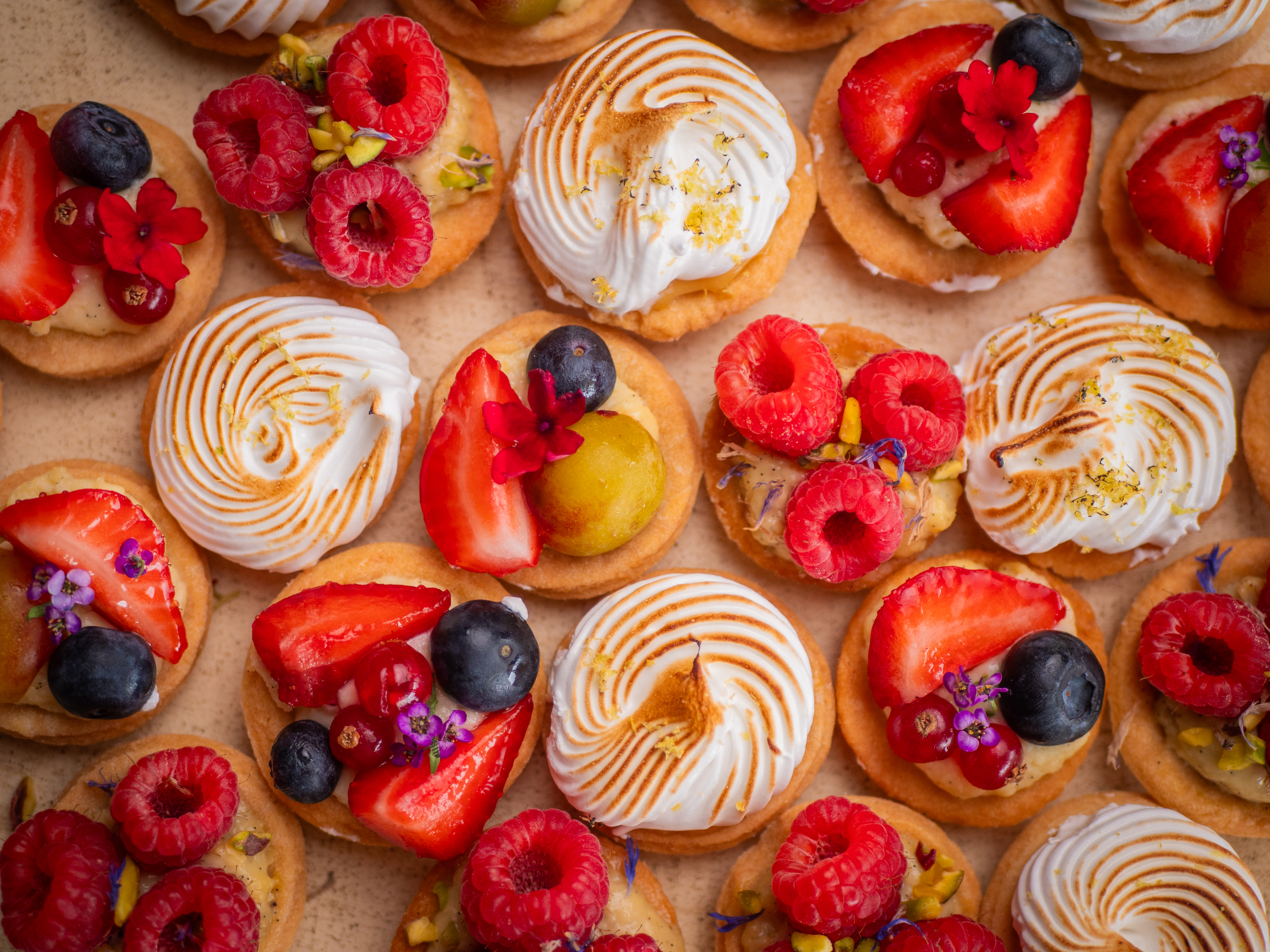 Assortiment de mini-tartelettes citron meringuées et aux fruits rouges, vue du dessus