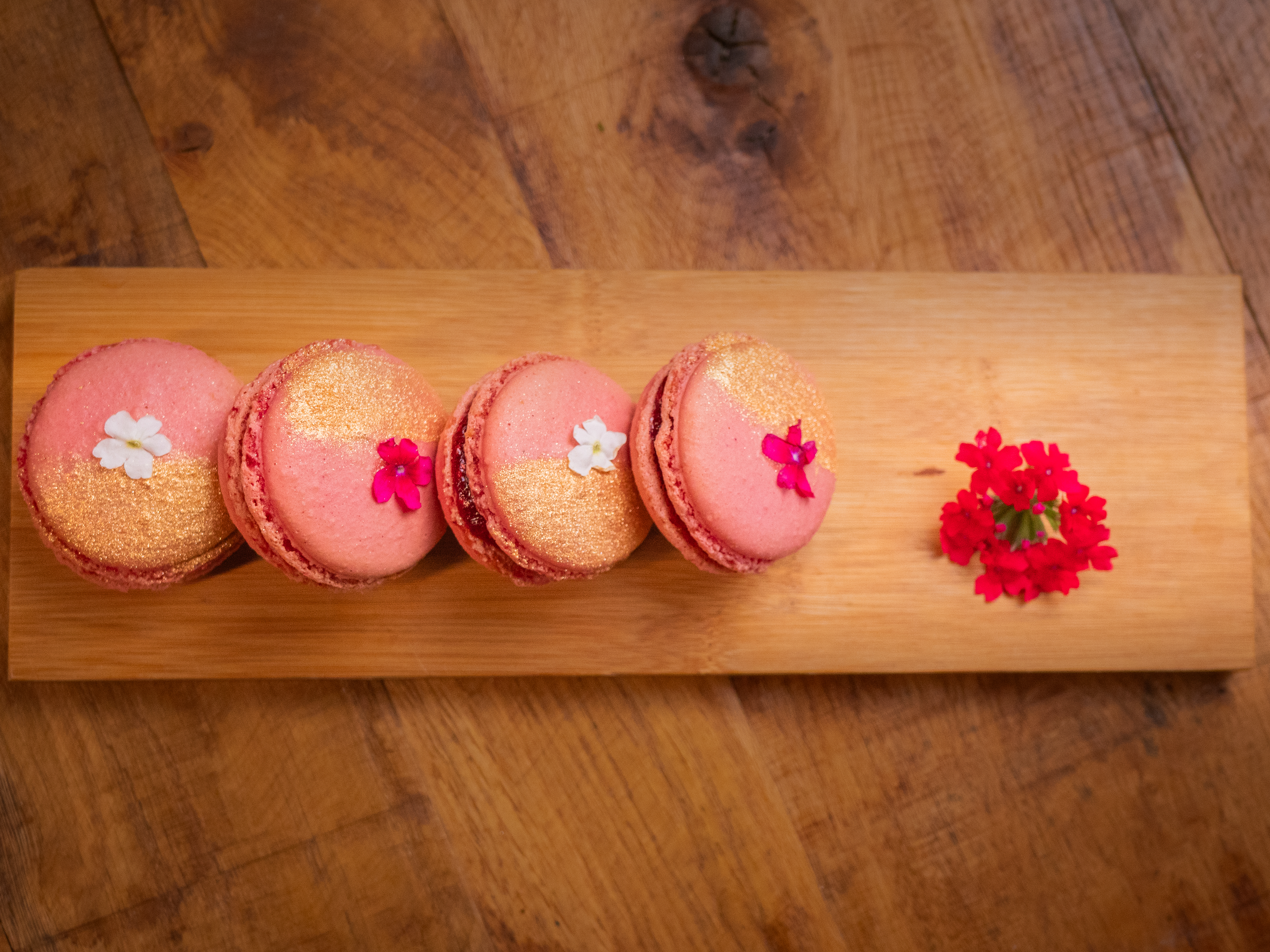 Macarons roses alignés sur une planche en bois, prêts à être servis